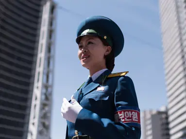 Seorang polisi wanita berada ditengah jalan untuk menagtur lalu lintas di Pyongyang, Korea Utara (5/6). Di Korea Utara menjadi polisi lalu lintas dipandang sebagai pekerjaan yang bergengsi. (AFP Photo/Ed Jones)