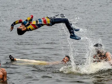 Pria dan anak muda Pakistan mendinginkan diri ke perairan Laut Arab saat musim panas di Karachi pada 5 Juli 2020. Mereka menghabiskan hari yang cerah dengan berenang di tengah pandemi virus corona. (Photo by Rizwan TABASSUM / AFP)