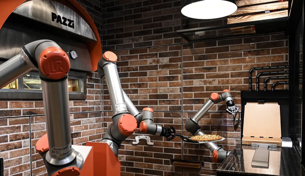 Foto yang diambil pada 1 Juli 2021 menunjukkan "Pazzi", robot pembuat pizza yang sedang bekerja di sebuah restoran di Paris. Setiap pizza umumnya hanya membutuhkan waktu sekitar lima menit untuk disiapkan dan dipanggang. (BERTRAND GUAY/AFP)