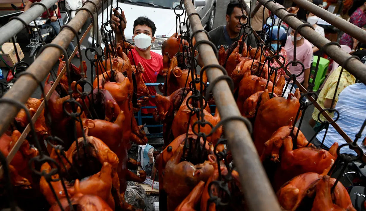 <p>Pekerja menurunkan babi panggang di pasar menjelang Tahun Baru Imlek yang menyambut Tahun Macan di Phnom Penh, Kamboja, Senin (31/1/2022). Menyambut Tahun Baru Imlek, warga Kamboja mempersiapkan daging babi panggang untuk sajian makan. (AFP/Tang Chhin Sothy)</p>