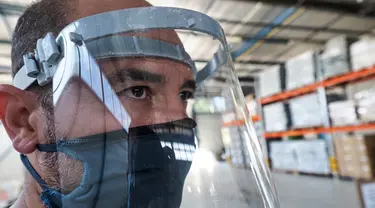 Pekerja memakai pelindung wajah yang terbuat dari kombinasi plastik dan tekstil di perusahaan Plaxtil, Chatellerault, Prancis, 25 Agustus 2020. Startup di Prancis, Plaxtil, mendaur ulang masker dan plastik untuk dijadikan pelindung wajah, pembuka pintu, dan pengencang masker. (GUILLAUME SOUVANT/AFP)