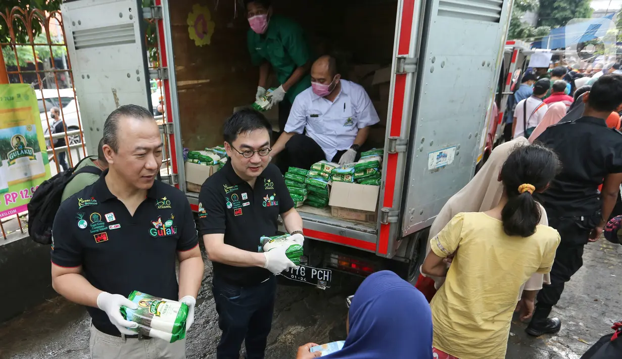 Direktur Sugar Group Companies Yusuf Sumartha dan Irwan Ang memberikan gula pasir kepada warga saat Operasi Pasar di Pasar Palmerah, Jakarta, Jumat (20/3/2020). Sugar Group Companies menjamin ketersediaan gula selama satu di 35 titik pasar wilayah DKI Jakarta dan Banten. (Liputan6.com/Fery Pradolo)