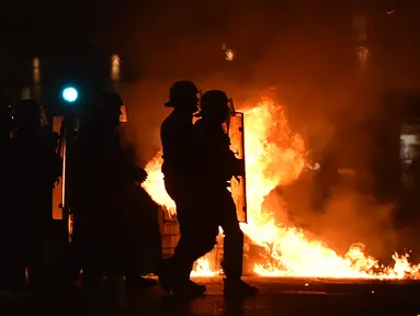 Polisi anti huru hara berjalan menghadapi massa yang melakukan pembakaran di Vieux Port di Marseille, Prancis (16/5). Kerusuhan ini disebabkan oleh fans Marseille yang tidak terima timnya kalah dalam final Liga Europa. (AFP Photo/Bertrand Langlois)