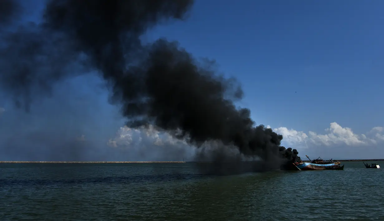 Asap hitam mengepul dari kapal asing ilegal yang ditenggelamkan di perairan Pelabuhan Perikanan Samudera Kutaraja, Banda Aceh, Aceh, Kamis (18/3/2021). Dua kapal asing asal Malaysia tersebut ditenggelamkan setelah diputus bersalah dalam perkara tindak pidana perikanan. (AFP/Chaideer Mahyuddin)