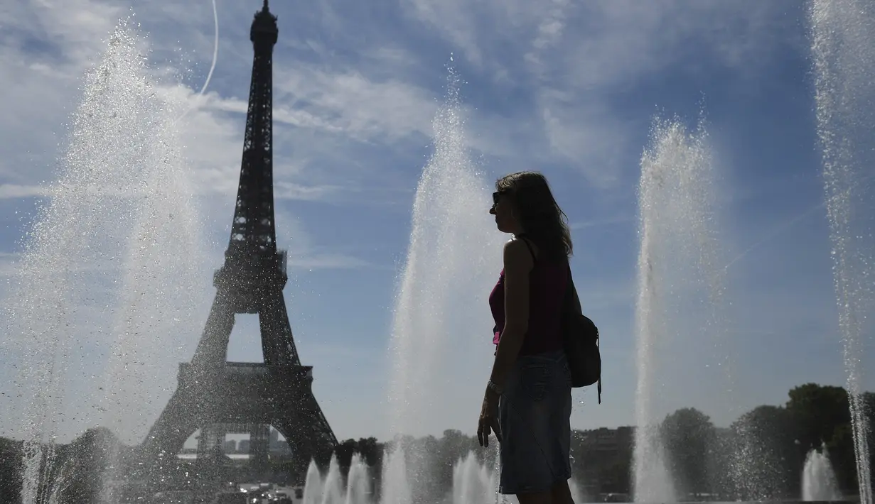 Seorang perempuan mendinginkan diri di dekat air mancur Trocadero, di tengah suhu tinggi di Paris, Kamis (16/6/2022). Prancis akan mengalami suhu yang memecahkan rekor mendekati 40 derajat Celcius pada Juni, karena gelombang panas dini yang diperkirakan akan melanda sebagian besar negara itu.
(JULIEN DE ROSA / AFP)