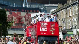 Dari atas bus, para pemain Arsenal melambaikan tangan kepada penggemar fanatik mereka saat parade kemenangan yang dimulai dari depan stadion Emirates, London, Inggris, (18/5/2014). (AFP PHOTO/Oliver Will)