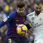 Bek Barcelona, Gerard Pique, berebut bola dengan striker Real Madrid, Karim Benzema, pada laga La Liga Spanyol di Stadion Camp Nou, Barcelona, Minggu (28/10). Barcelona menang 5-1 atas Madrid. (AFP/Lluis Gene)