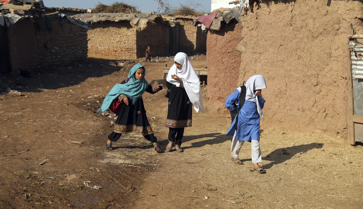 Anak-anak sekolah pengungsi Afghanistan berjalan setelah mengikuti kelas di sekolah darurat di pinggiran Islamabad, Pakistan, Rabu (29/12/2021). (AP Photo/Rahmat Gul)