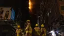 Petugas pemadam kebakaran memadamkan api di lokasi konstruksi di Hong Kong, Jumat (3/3/2023). Dinas Kebakaran pun bergerak cepat untuk melakukan pemadaman. (AP Photo/Louise Delmotte)