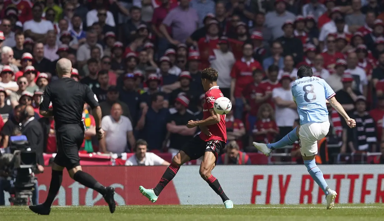 Pemain Manchester City, Ilkay Gundongan (kanan), menendang bola ke gawang Manchester United  yang membuahkan gol cepat di detik ke-12 dalam pertandingan final FA Cup 2022/2023 yang berlangsung di Wembley Stadium, Sabtu (3/6/2023). (AP Photo/Dave Thompson)