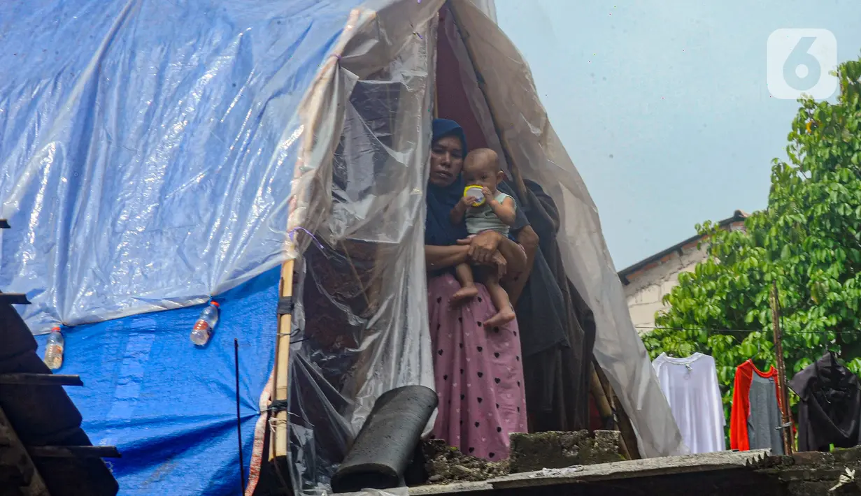 Warga beraktivitas pada tenda darurat yang dibangun di atas rumah pasca banjir melanda kawasan Pejaten Timur, Jakarta Selatan, Senin (8/1/2024). (merdeka.com/Arie Basuki)
