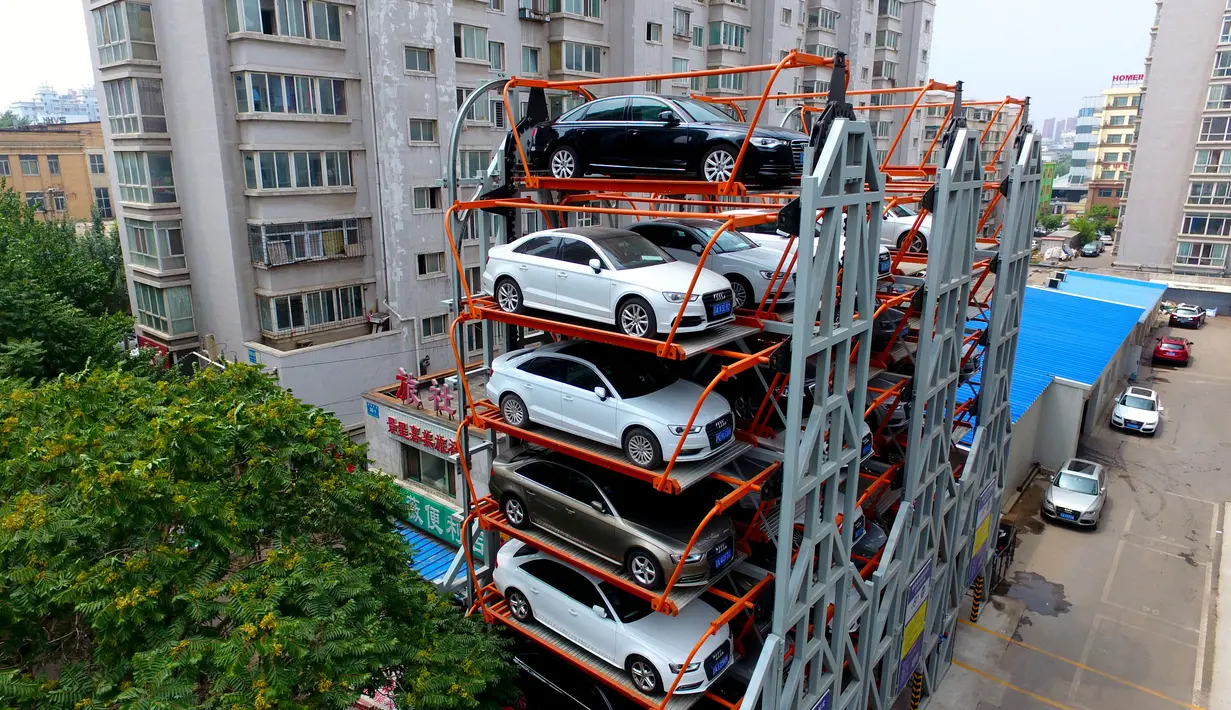 Struktur dari parkir bertingkat tiga dimensi yang terletak di antara bangunan tempat tinggal apartemen di Shenyang, Provinsi Liaoning, China (19/6). Fasilitas parkir yang tak memakan banyak tempat ini disediakan untuk umum. (AFP Photo/Str/China Out)