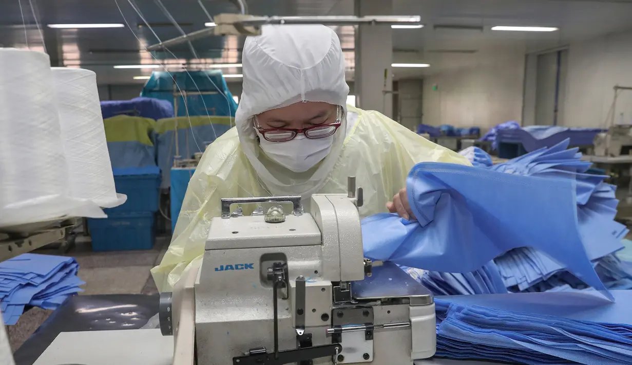 Pekerja memproduksi pakaian pelindung di sebuah pabrik di Nantong, Provinsi Jiangsu, China, Senin (27/1/2020). Pakaian pelindung tersebut diproduksi untuk mendukung pasokan bahan medis saat wabah virus corona melanda China. (STR/AFP)
