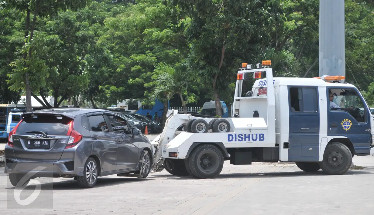 Petugas Dishub DKI Jakarta menderek mobil yang terkena razia parkir liar di penampungan derek parkir liar, Monas, Jakarta, Senin (13/3). Pada periode Januari-Febuari, Dishub menindak 6.437 kendaraan dengan sanksi ditilang. (Liputan6.com/Yoppy Renato)