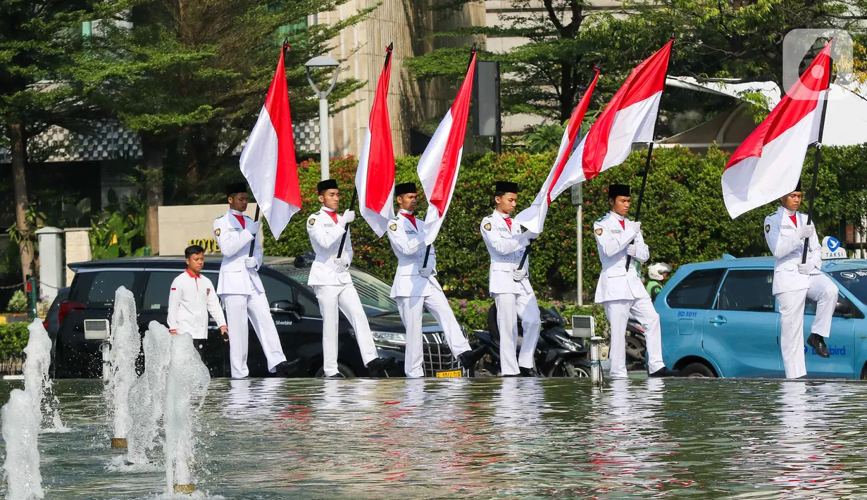Sejumlah pasukan pengibar bendera (Paskibra) berbaris membawa bendera Merah Putih di Bundaran Hotel Indonesia (HI), Jakarta, Kamis (15/8/2024). (Liputan6.com/Herman Zakharia)