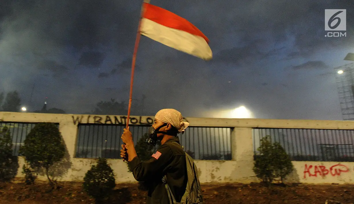 Seorang pengunjuk rasa membawa bendera melintas di Jalan Pejompongan, Jakarta, Senin (30/9/2019). Hingga saat ini, aparat kepolisian dibantu personel TNI terus mendorong dan membubarkan massa aksi hingga ke kawasan Slipi. (merdeka.com/Arie Basuki)