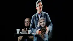 Sepasang tamu duduk sambil mengamati hologram tiga dimensi (3D) calon presiden indepeden Prancis dari kelompok sayap kiri, Jean-Luc Melenchon, yang sedang berpidato di lokasi kampanye di Saint-Denis, dekat Paris, Minggu (5/2). (AP Photo/Kamil Zihnioglu)