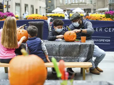 Warga New York mengukir labu dalam persiapan Halloween di Rockefeller Center (22/10/2020). Para pekerja di Rockefeller Center beristirahat sejenak untuk mempelajari cara mengukir labu dengan benar dari Maniac Pumpkin Carvers, seniman dari Brooklyn . (Diane Bondareff/AP Images for Tishman Speyer)