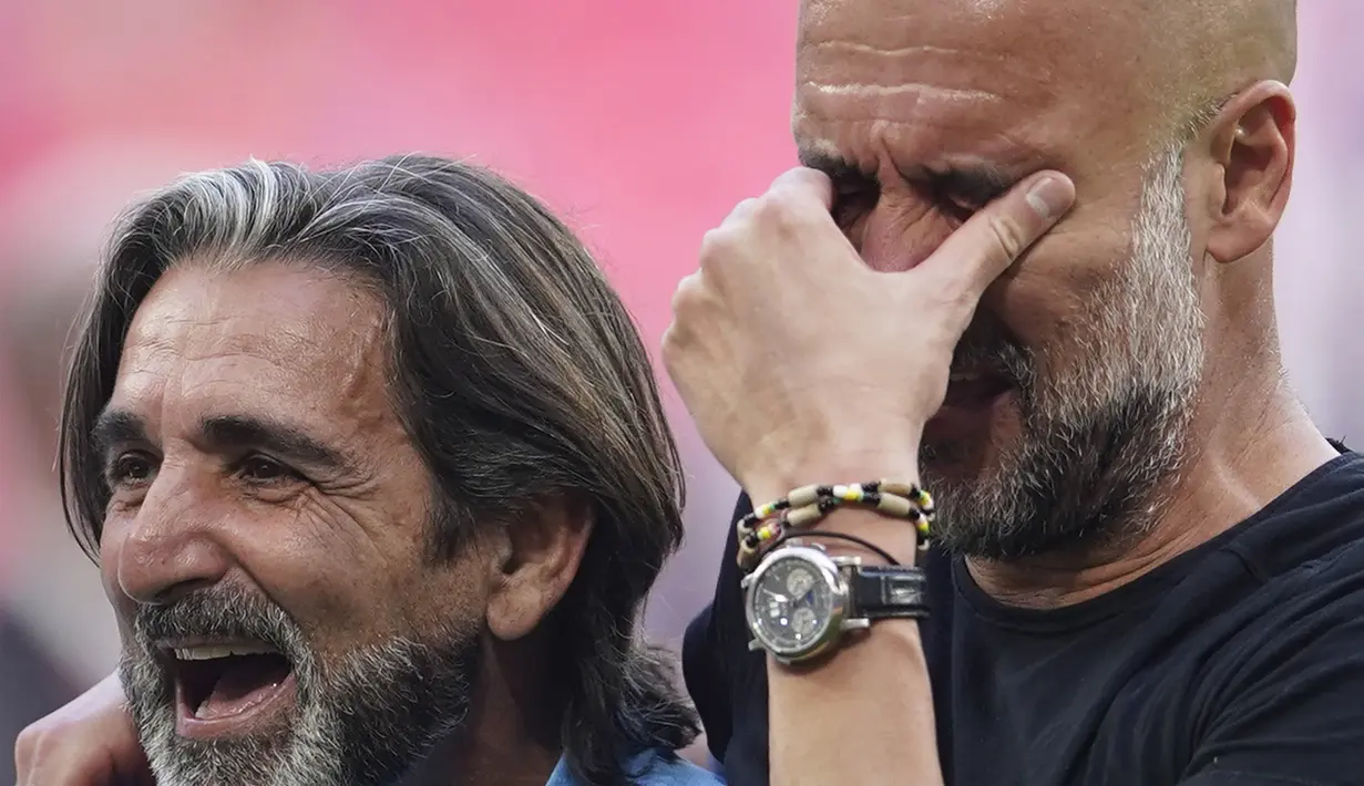 Pelatih Manchester City, Pep Guardiola (kanan), menyeka air matanya setelah berhasil membawa timnya keluar sebagai juara Piala FA 2022/2023 dalam pertandingan final FA Cup melawan Manchester United yang berlangsung di Wembley, Sabtu (3/6/2023) WIB. (AP Photo/Dave Thompson)