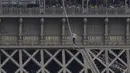 Akrobatik Nathan Paulin tampil untuk kedua kalinya meniti seutas tali slackline pada ketinggian 70 meter antara Menara Eiffel dan Theater Chaillot di Paris, Minggu (19/9/2021). Pada 2019, pria Prancis itu melakukan slackline walk setinggi 150 meter dengan panjang 510 meter. (AP Photo/Francois Mori)