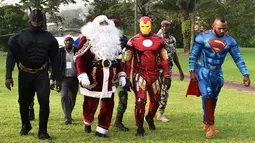 Sejumlah pria mengenakan kostum pahlawan super berjalan di istana kepresidenan di Pantai Gading (23/12). Mereka mengenakan kostum tokoh pahlawan super seperti Batman, Santa Claus, Iron Man dan Superman. (AFP Photo/Sia Kambou)