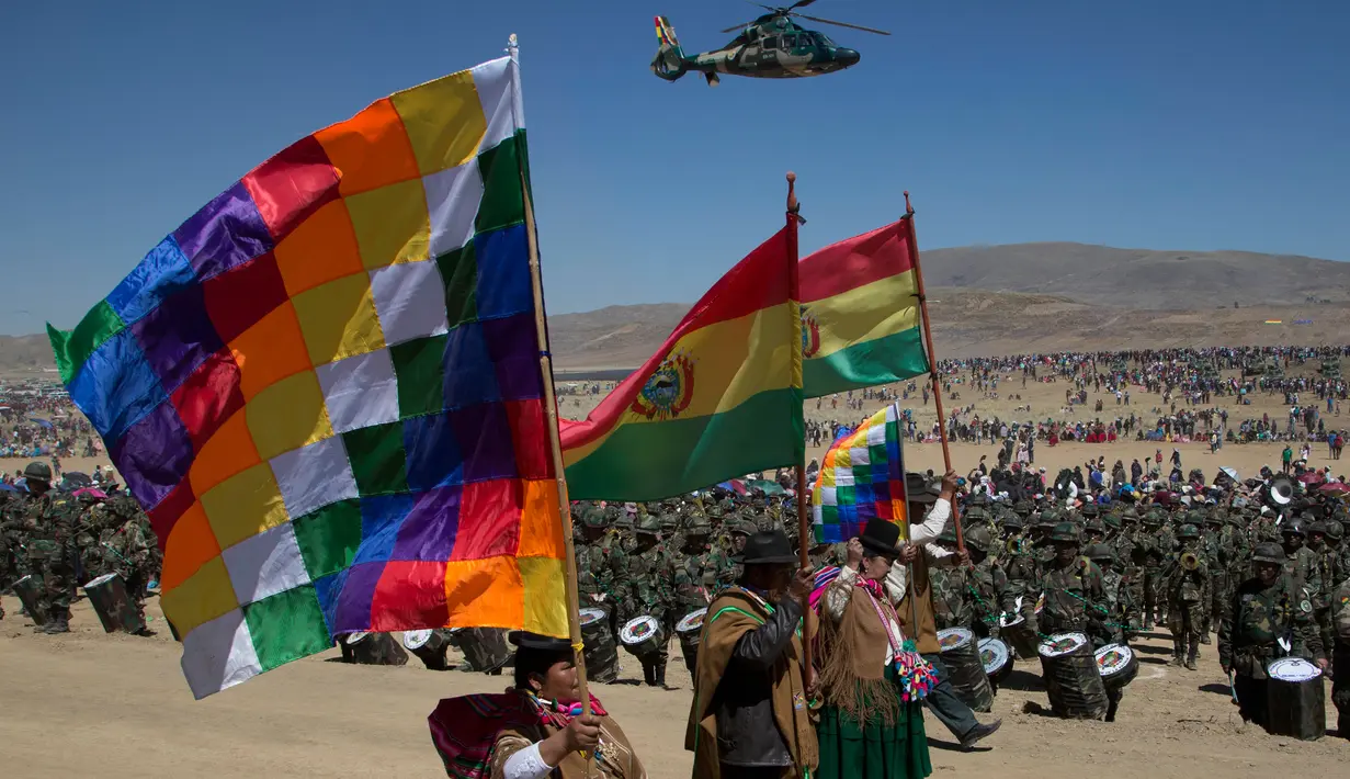 Suku pribumi Aymara membawa bendera Bolivia dan Wiphala saat mengikuti upacara ulang tahun tentara Bolivia ke-192 di Kjasina, Bolivia (7/8). Upacara ini digelar ditengah gurun karena ingin melibatkan penduduk pribumi asli Bolivia. (AP Photo/Juan Karita)