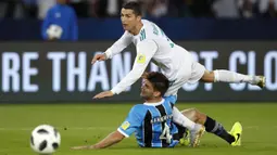 Striker Real Madrid, Cristiano Ronaldo, terjatuh saat berebut bola dengan pemain Gremio, Walter Kannemann, pada final Piala Dunia Antarklub di Stadion Syeikh Zayed, Abu Dhabi, Sabtu (16/12/2017). Real Madrid menang 1-0 atas Gremio. (AP/Hassan Ammar)