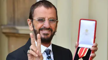 Ringo Starr berpose di Istana Buckingham, di London, Inggris (20/3). Mantan drummer The Beatles ini mendapat gelar kebangsawanan dari Pangeran William. Ia diberi gelar 'Sir' atas jasanya dalam dunia musik. (John Stillwell / Pool Photo via AP)