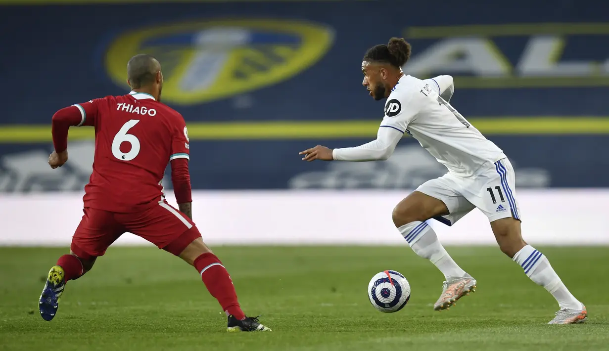Pemain Leeds United Tyler Roberts (kanan) menggiring bola mencoba melewati pemain Liverpool Thiago pada pertandingan Liga Inggris di Stadion Elland Road, Leeds, Inggris, Senin (19/4/2021). Pertandingan berakhir dengan skor 1-1. (Paul Ellis/Pool via AP)