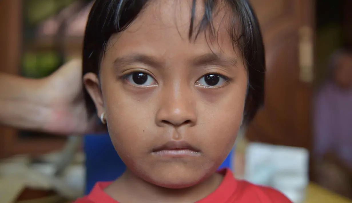 Ekspersi seorang anak saat menunggu giliran disuntik difteri di sebuah klinik desa di Jakarta (11/12). Wabah Difteri ini telah menewaskan puluhan orang. (AFP Photo/Adek Berry)
