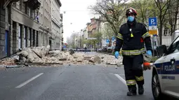Seorang pemadam kebakaran Kroasia berjalan melewati puing-puing setelah gempa di jalan-jalan pusat kota Zagreb (22/3/2020). Lindu merusak sejumlah gedung dan membuat banyak mobil hancur karena terjangan batu. (AFP/Damir Sencar)
