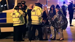 Personel darurat berbicara kepada warga di luar Manchester Arena, Inggris, usai ledakan di dalam tempat konser penyanyi Ariana Grande, Senin (22/5). Belum diketahui penyebab ledakan maupun pelaku dalam serangan tersebut. (Peter Byrne/PA via AP)