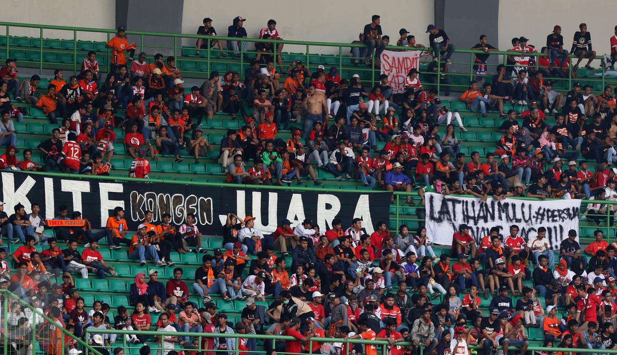 Suporter membentangkan spanduk saat menyaksikan laga Persija melawan Mitra Kukar pada lanjutan Liga 1 Indonesia di Stadion Patriot Candrabhaga, Bekasi, Minggu (14/5). Laga kedua tim berakhir imbang 1-1. (Liputan6.com/Helmi Fithriansyah)