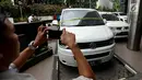 Seorang pria mengambil gambar salah satu mobil milik bos PT First Travel Andika Surachman dan Anniesa Desvitasari Hasibuan yang terparkir di Bareskrim Polri, Gedung Kementerian Kelautan dan Perikanan, Jakarta, Jumat (25/8). (Liputan6.com/Johan Tallo)