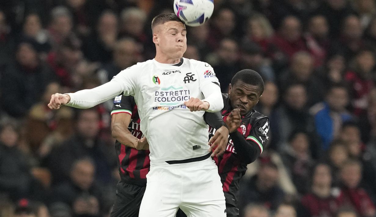 Pemain Spezia, Emil Holm melompat untuk merebut bola dengan pemain AC Milan, Pierre Kalulu selama pertandingan lanjutan Liga Serie A Italia di stadion San Siro, di Milan, Italia, Minggu (6/11/2022). Kemenengan ini membuat AC Milan terus menempel Napoli dengan 29 poin di posisi kedua klasemen Serie A, berjarak enam poin. (AP Photo /Antonio Calanni)