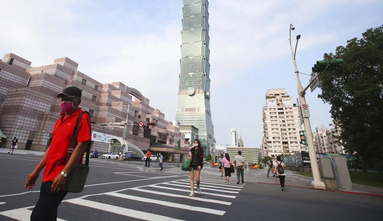 Warga memakai masker untuk melindungi dari penyebaran COVID-19 saat melewati Gedung Taipei 101 di Taipei, Taiwan, Sabtu (15/5/2021). Taiwan yang membuat iri dalam menahan COVID-19 memberlakukan pembatasan baru di ibu kota saat memerangi wabah terburuk sejak pandemi. (AP Photo/Chiang Ying-ying)