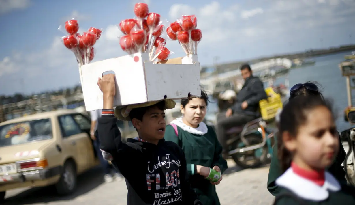 Haitham Khzaiq (16), anak Palestina yang berhenti sekolah enam bulan lalu menjual apel manis dan menghasilkan sekitar 20 Shekels ($ 5.1) per hari di Pelabuhan Kota Gaza, (17/3). Khzaiq mempunyai mimpi menjadi Insinyur arsitek. (REUTERS/Mohammed Salem)