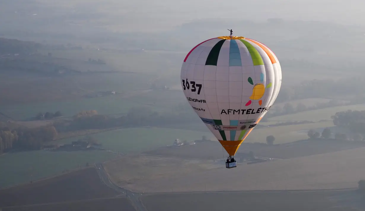 Balonist Prancis Remi Ouvrard mencoba memecahkan rekor dunia dengan berdiri di atas balon udara panas di Chatellerault, Rabu (10/11/2021). Ketinggian harus sama dengan nomor telepon kampanye Telethon 36-37, penggalangan dana tahunan Prancis untuk penelitian medis. (Guillaume SOUVANT/AFP)