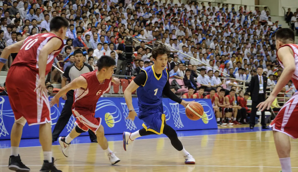 Pemain Korea Selatan (Biru) membawa bola dari kawalan pemain Korea Utara (merah) selama pertandingan basket pria di Stadion Indoor Ryugyong Chung Ju-Yung, Pyongyang (5/7). (AFP Photo/Kim Won-Jin)