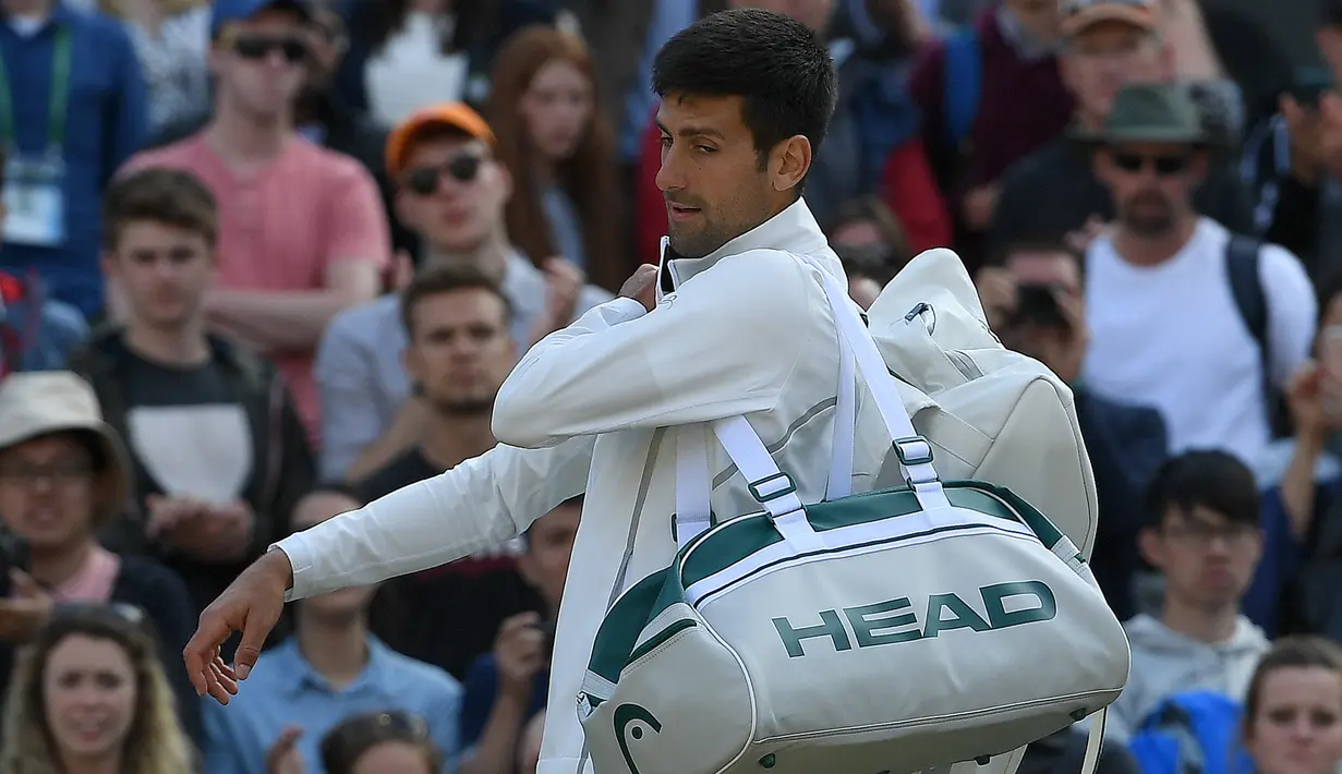 Petenis Serbia, Novak Djokovic meninggalkan lapangan usai memutuskan mundur pada babak perempatfinal Wimbledon 2017, Rabu (12/7).  Pada laga tersebut Djokovic tak kuasa menahan rasa sakit saat bertemu Tomas Berdych asal Ceko. (Glyn KIRK / AFP)