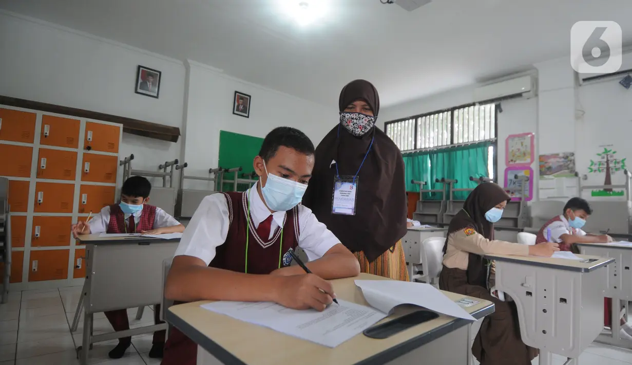 Guru mangawasi murid saat kegiatan  KSN  seleksi Tingkat SD/ MI Kecamatan Cinere  mata pelajaran IPA di SDIT MU, Depok, Jawa Barat, Sabtu (6/3/2021). Pelaksanaan KSN tahun ini dilaksanakan secara tatap muka dengan menerapkan protokol kesehatan. (merdeka.com/Arie Basuki)
