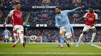 Gelandang Manchester City, Bernardo Silva (tengah) melepaskan umpan yang berusaha diblok bek Arsenal, Ben White pada laga pekan ke-30 Premier League 2023/2024 di Etihad Stadium, Manchester, Minggu (31/3/2024). (AP Photo/Dave Thompson)