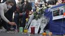 Seorang wanita menyalakan lilin di alun-alun Republique selama demonstrasi di Paris (18/10/2020). Samuel Paty dipenggal pada hari Jumat di Conflans-Sainte-Honorine oleh seorang pengungsi Chechnya. (AP Photo/Michel Euler)