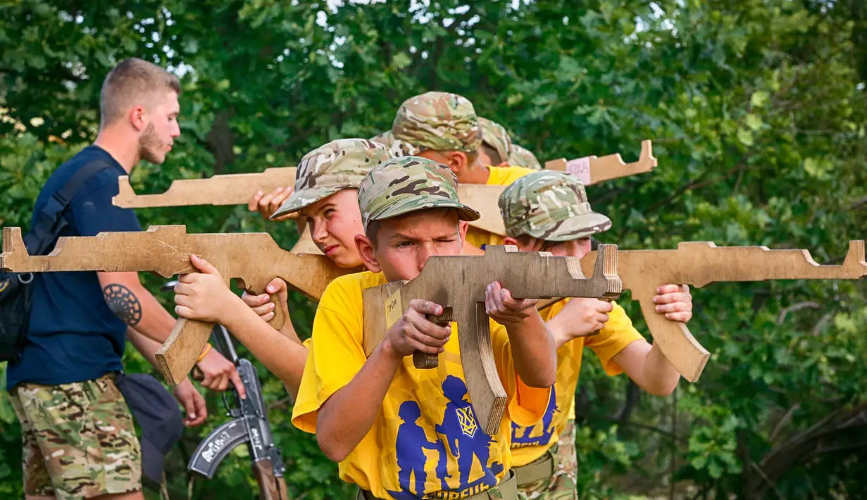Siswa memegang senapan kayu saat mengikuti pelatihan di kamp paramiliter di Kiev, Ukraina, (8/7). Konflik yang terjadi di bagian timur Ukraina membuat beberapa orang tua sangat ingin memastikan anak-anak mereka siap jika perang. (AP Photo/Efrem Lukatsky)