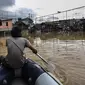 Seorang pria menaiki perahu karet saat menyusuri banjir yang melanda Jalan Bina Warga Rt 005/Rw 07 Kelurahan Rawa Jati, Jakarta, Senin (8/2/2021). Banjir setinggi 60-190 cm tersebut disebabkan oleh luapan air Sungai Ciliwung dan curah hujan Jakarta yang tinggi. (Liputan6.com/Johan Tallo)