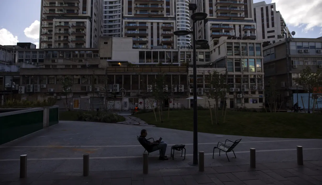 Seorang pria bekerja dengan laptopnya di pusat kota Tel Aviv, Israel, Kamis(2/12/2021). Economist Intelligence Unit (EIU) pada 1 Desember mengumumkan Tel Aviv telah menggeser posisi Paris sebagai kota termahal di dunia untuk ditinggali. (AP Photo/Oded Balilty)