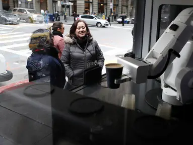 Pelanggan menyaksikan robot barista membuat kopi di Cafe X, San Francisco, California, AS, Selasa (12/2). Cafe X menggunakan robot untuk menyajikan makanan dan minuman. (Justin Sullivan/Getty Images/AFP)