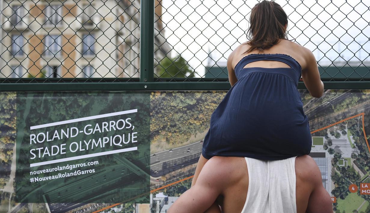 Aksi seorang wanita yang duduk di atas bahu kekasihnya saat menonton pertandingan tenis di ajang Roland Garros 2017, Prancis Terbuka, Paris,  (28/5/2017).  (AFP/Gabriel Bouys)