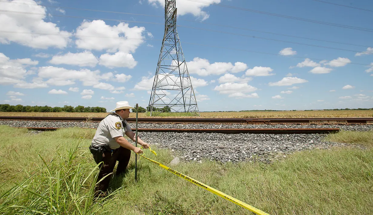 Sheriff Caldwel County, Sean Quinn memasang garis polisi di lokasi jatuhnya balon udara di Maxwell, wilayah Texas, Sabtu (30/7). Balon udara berpenumpang sedikitnya 16 orang itu tiba-tiba terbakar dan jatuh di areal padang rumput. (REUTERS)