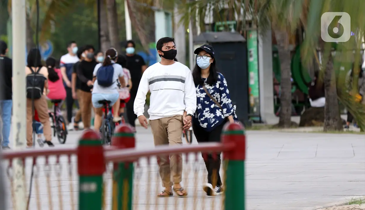 Pengunjung berpasangan menikmati suasana pantai di Taman Impian Jaya Ancol, Jakarta, Kamis (29/10/2020). Libur panjang di masa pemberlakuan PSBB transisi Jakarta dimanfaatkan warga untuk mengunjungi lokasi-lokasi wiisata. (Liputan6.com/Helmi Fithriansyah)